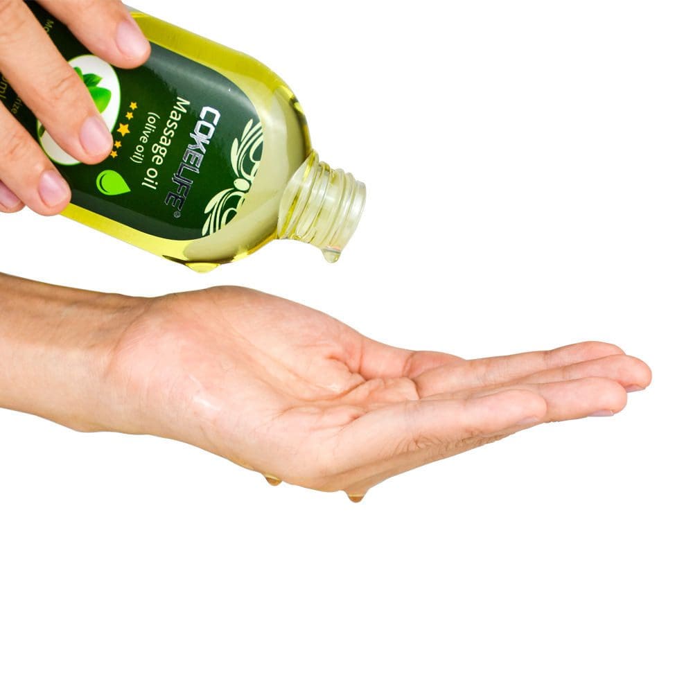 A person pouring olive oil into their palm from a green bottle.