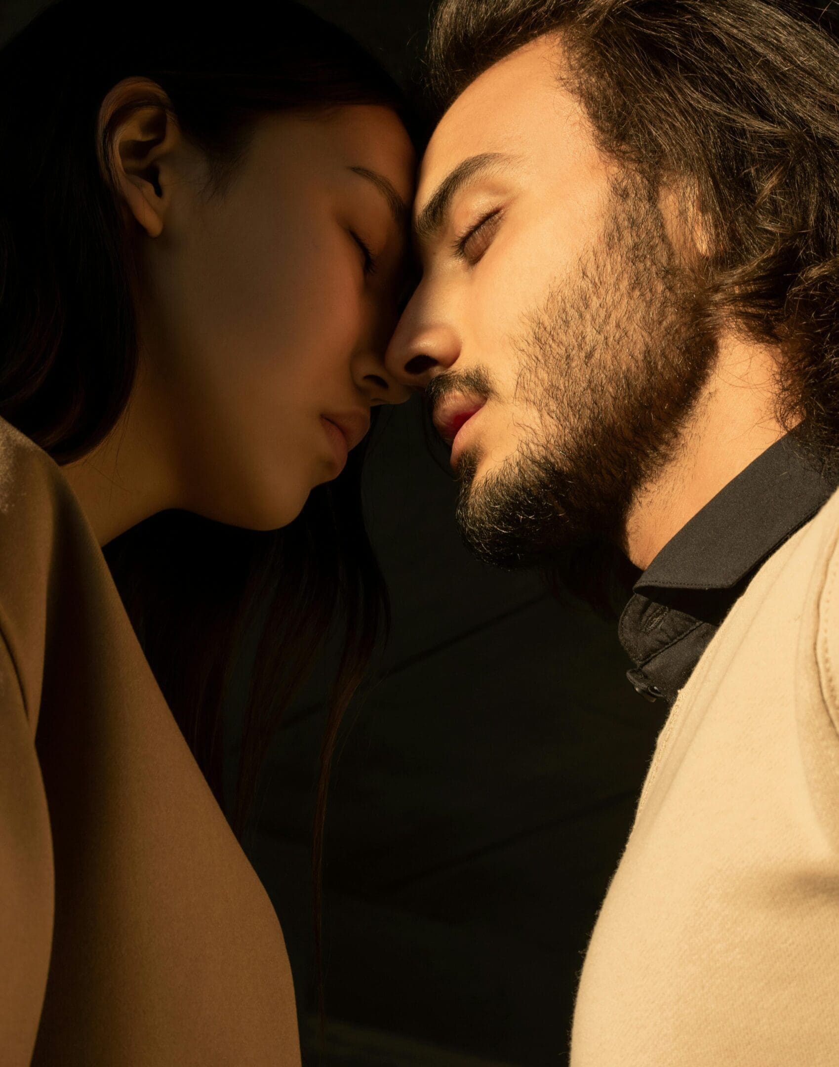 A close, intimate moment between a man and woman with their foreheads touching.