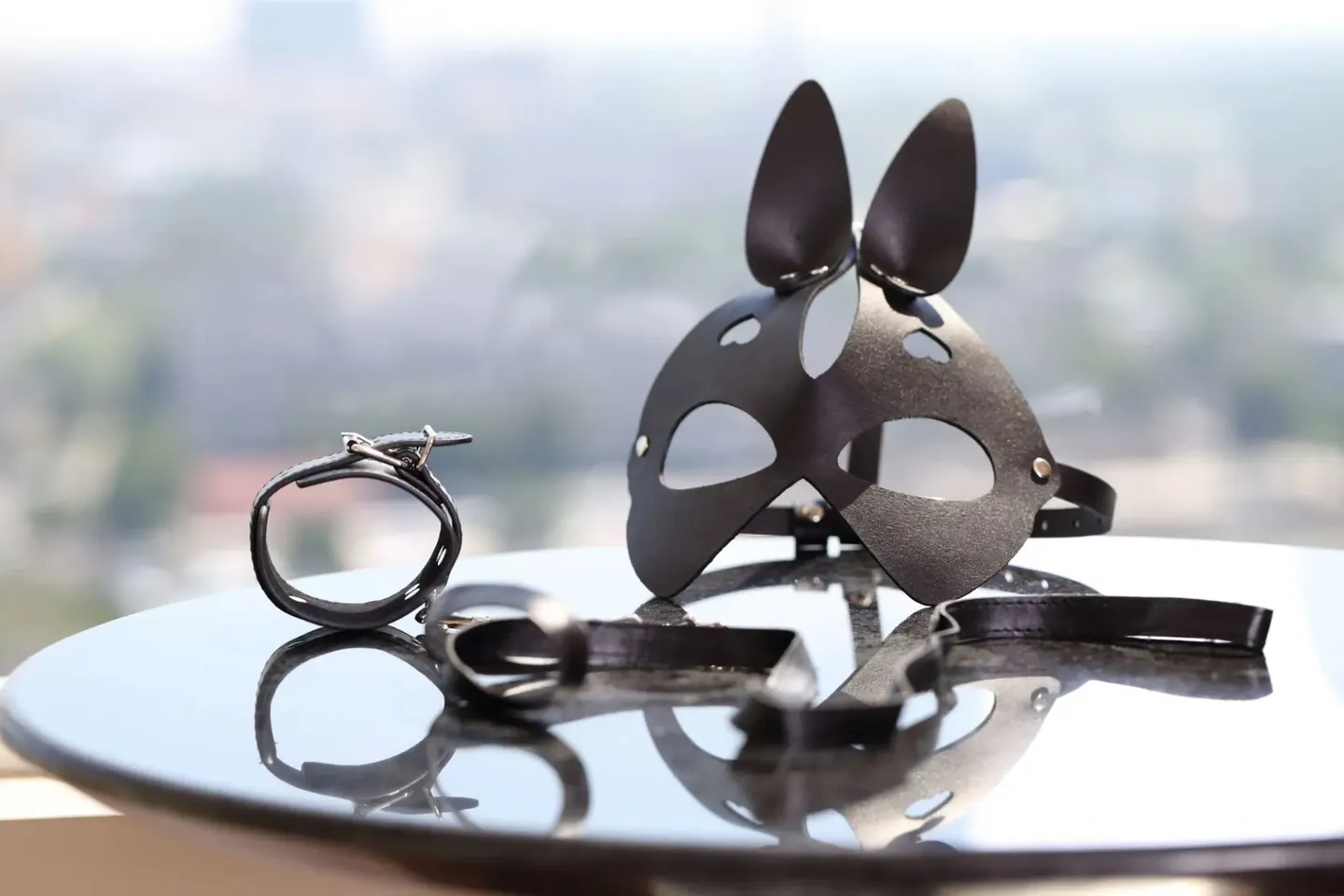 Black bunny mask and handcuffs on a reflective surface.